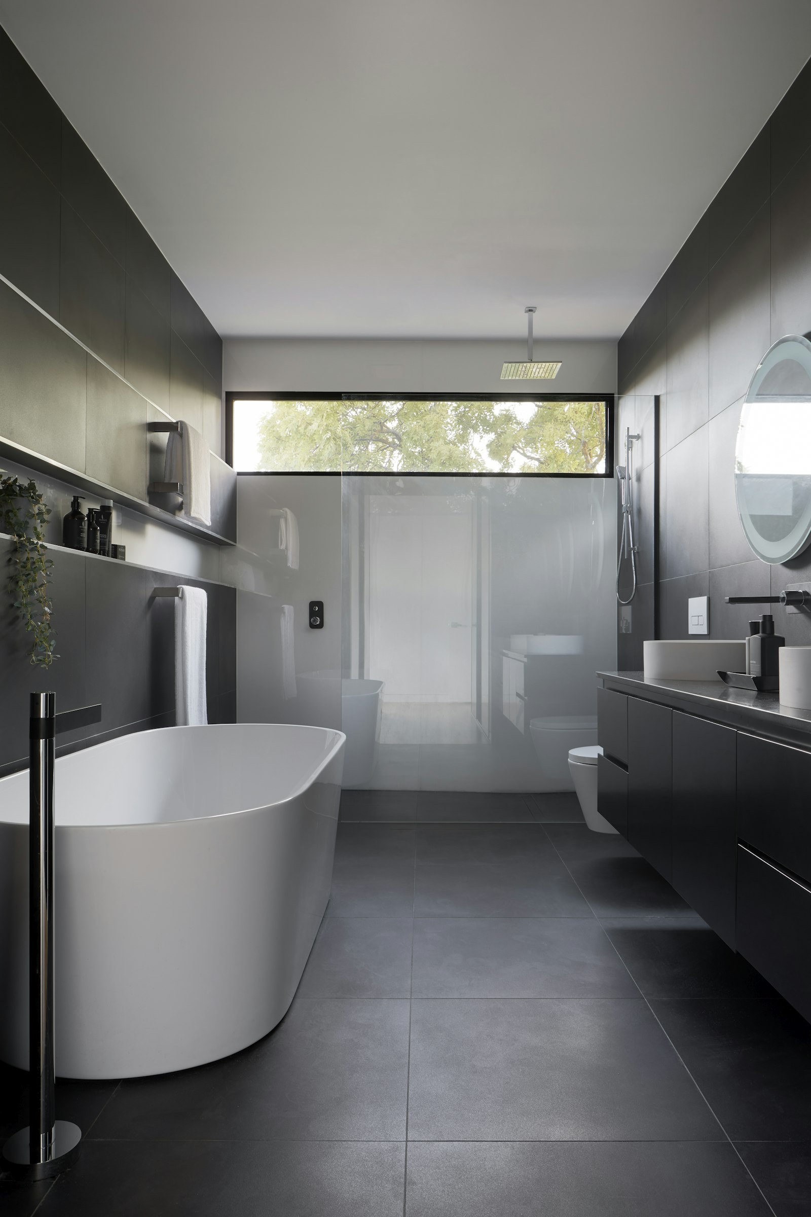 Modern remodeled bathroom with a freestanding tub, walk-in shower, and dark tile