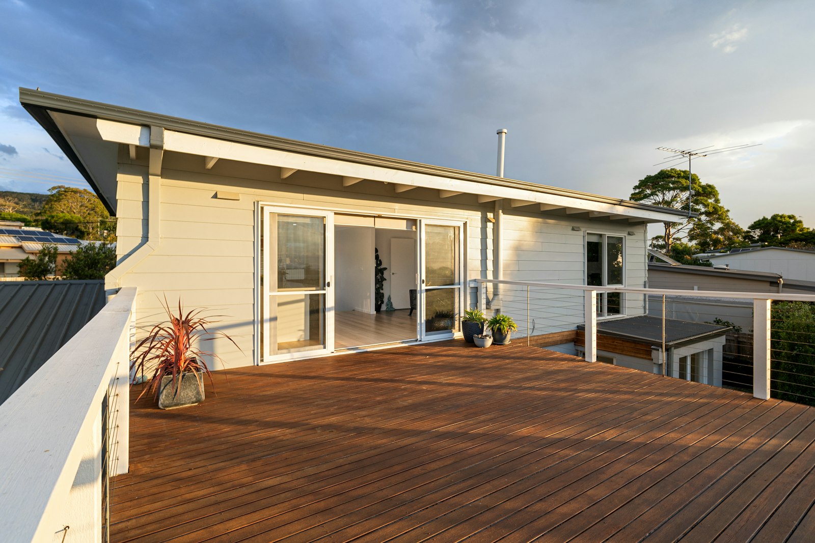 Newly built wood deck with cable railing opening to a renovated home